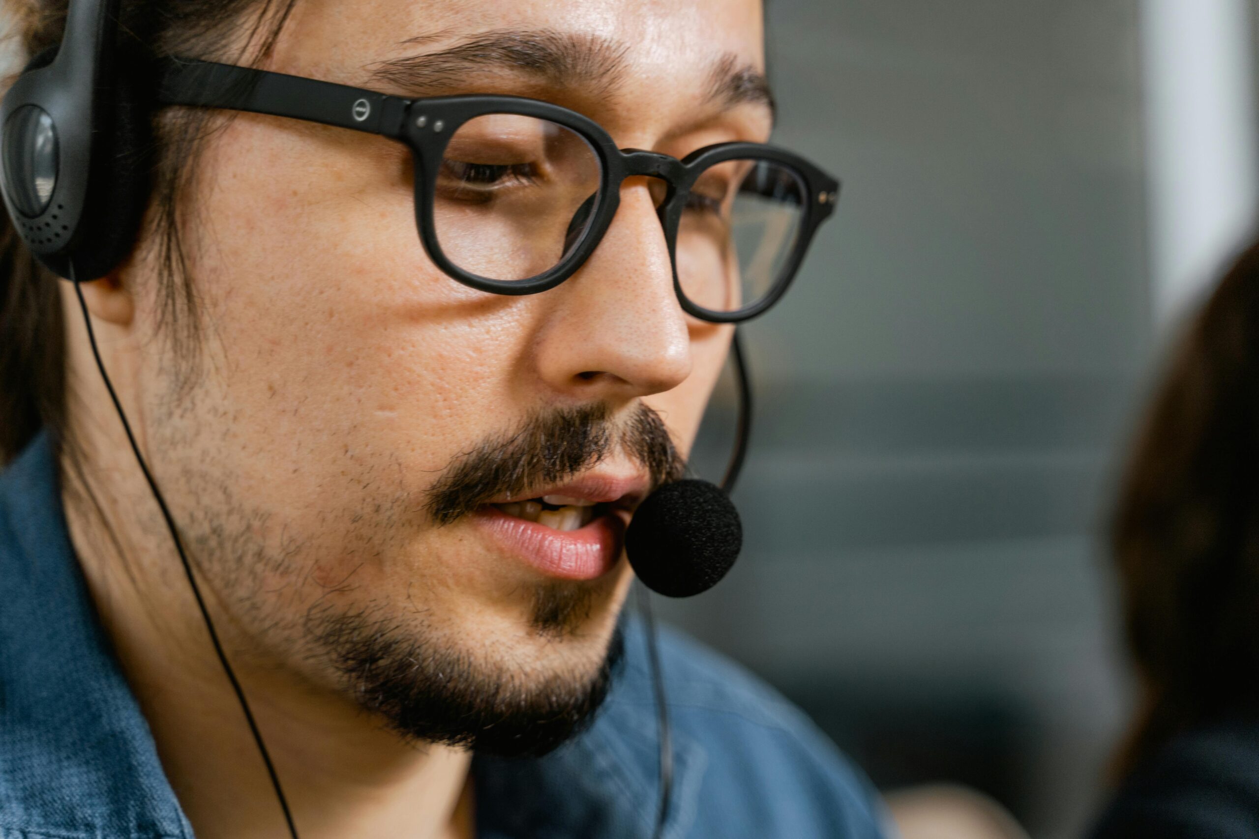 Close-up of a call center agent with a headset and eyeglasses providing customer support.